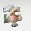 A single jigsaw piece from Schiffer Publishing, Ltd.'s The Tiniest Giant 4-in-1 Puzzle Set features a brown-capped acorn on a light, green-gray background—ideal for kids and nature puzzle fans.