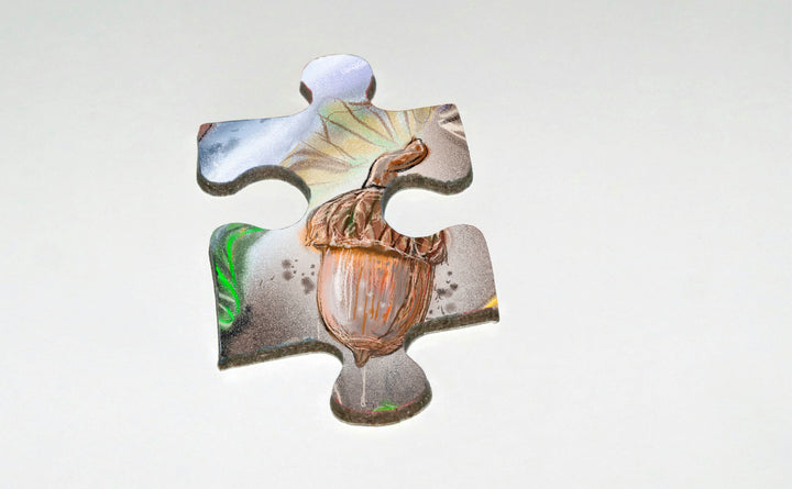 A single jigsaw piece from Schiffer Publishing, Ltd.'s The Tiniest Giant 4-in-1 Puzzle Set features a brown-capped acorn on a light, green-gray background—ideal for kids and nature puzzle fans.