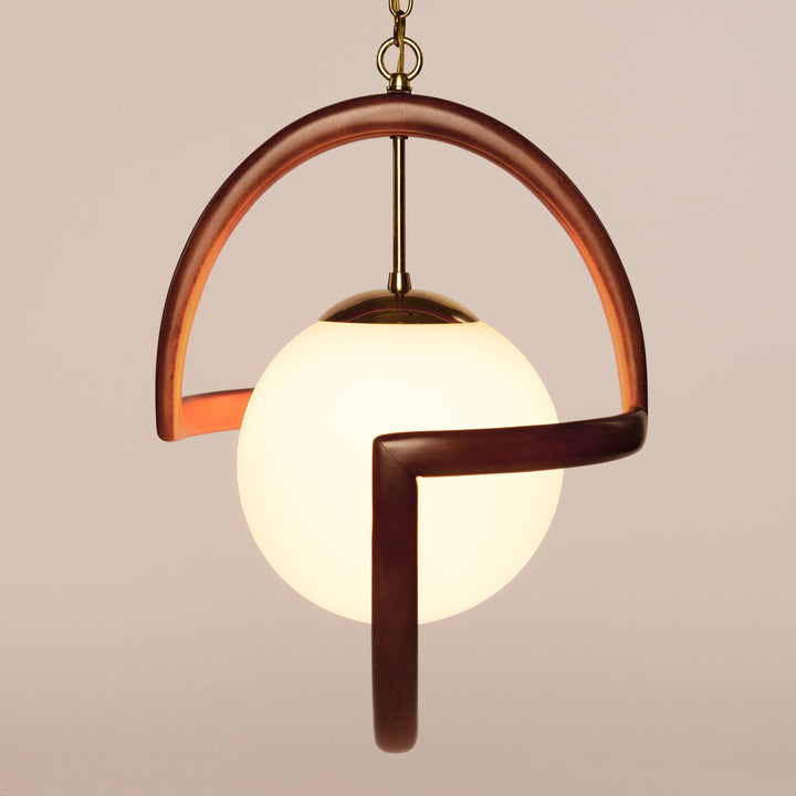 The Modeline of California by Schiffer Publishing, Ltd. is a pendant light with a glowing white globe in a curved wooden frame and brass accents, suspended from a gold chain—perfect for midcentury modern interiors.