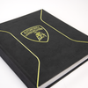 The Automobili Lamborghini Special Edition by Schiffer Publishing, Ltd. is a black book with yellow trim, suede-like cover, embossed lower-right text, and the iconic bull logo—perfect for luxury sportscar enthusiasts.