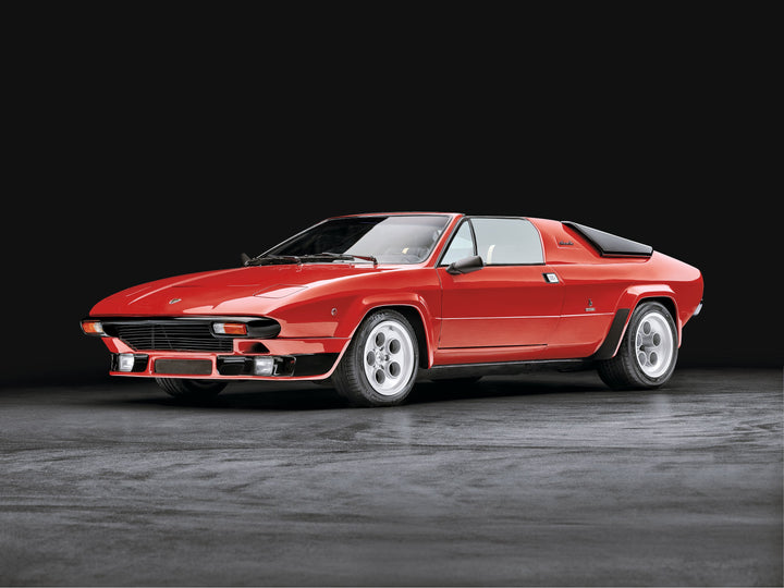 The Automobili Lamborghini Special Edition by Schiffer Publishing, Ltd. is showcased as a classic red sports car with a sleek, angular design and pop-up headlights, parked on a smooth surface against a dark background.
