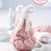 The Super Simple Finger Knitting Kit Sugarplum Christmas Tree by Schiffer Publishing, Ltd. sits on a table with a big white bow, surrounded by a snowflake candle holder and two silver trees in the background.
