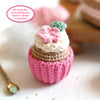 The Crochet Cafe Amigurumi Kit Cupcake by Schiffer Publishing, Ltd. includes supplies to make a cupcake with a pink base, beige middle, white top, pink flower and green leaf—perfect for beginners! Comes with a small spoon and text bubble.