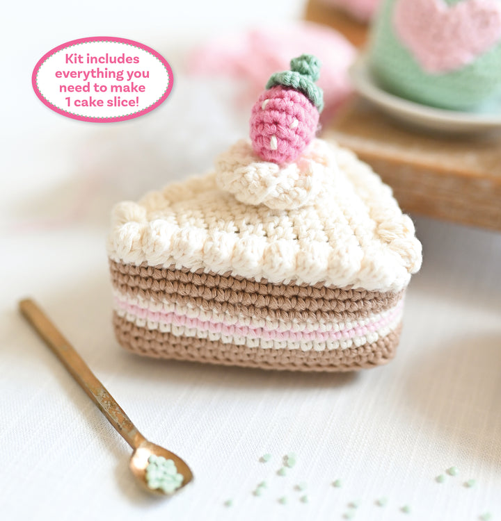 The Crochet Cafe Amigurumi Kit Cake Slice by Schiffer Publishing, Ltd. includes all you need to crochet a cake slice with cream, pink, and brown layers, topped with a strawberry. Perfect for beginners—make your own sweet treat!.
