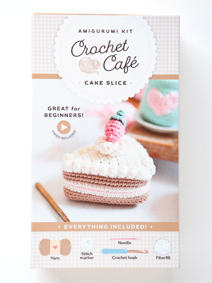 The Crochet Cafe Amigurumi Kit Cake Slice by Schiffer Publishing, Ltd. is a beginner crochet kit that includes yarn, needle, stitch marker, crochet hook, fiberfill, and makes a cute cake slice with a strawberry on top.