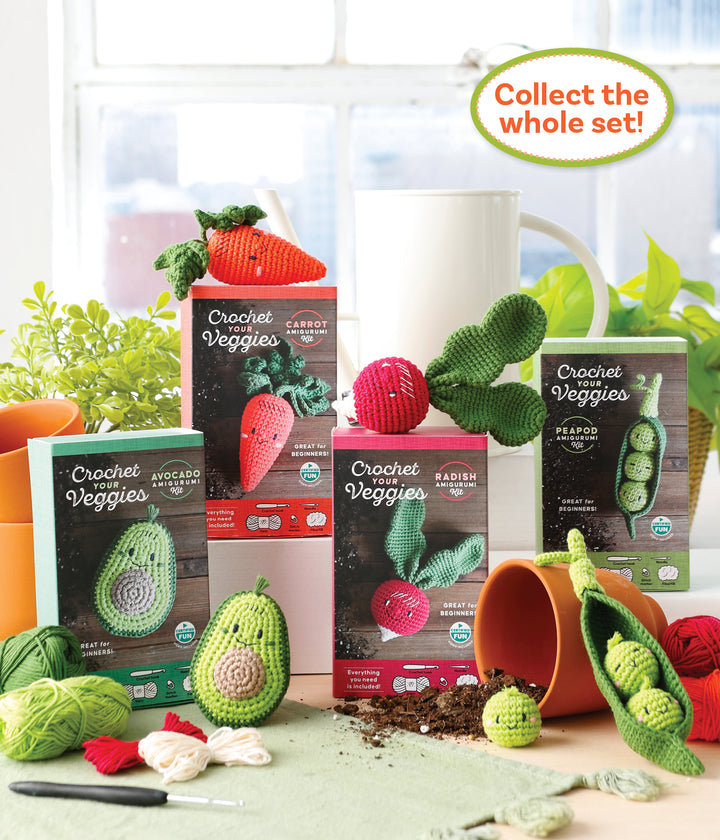 The Crochet Your Veggies Amigurumi Kit Carrot by Schiffer Publishing, Ltd. is shown with finished carrot, avocado, and radish amigurumi, yarn, hooks, and a tipped plant pot, plus a “Collect the whole set!” sign in the upper right.
