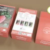 Three coral-pink boxes of the Schiffer Publishing, Ltd. Crochet Your Veggies Amigurumi Kit Carrot display a photo of a crocheted carrot, list kit contents and instructions, and reveal all materials needed for beginners to crochet one carrot.