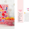 The Handmade Happiness Yarn Crafts art piece by Schiffer Publishing, Ltd. adds vibrant style to your home décor, displayed on a white surface beside a pink pedestal bowl of citrus fruit and a white hexagon-tiled wall.