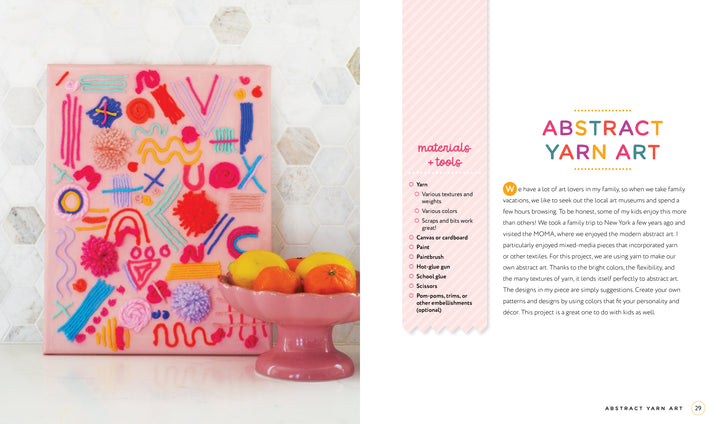The Handmade Happiness Yarn Crafts art piece by Schiffer Publishing, Ltd. adds vibrant style to your home décor, displayed on a white surface beside a pink pedestal bowl of citrus fruit and a white hexagon-tiled wall.