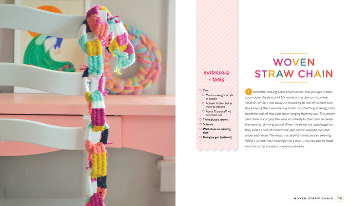 A vibrant woven straw chain from “Handmade Happiness Yarn Crafts” by Schiffer Publishing, Ltd. decorates a white chair. Beside it lies a printed guidebook with instructions on a white and pink background.