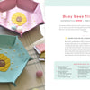 HeartFELT Crafts to Make and Give by Schiffer Publishing, Ltd. features pink and teal felt hexagon trinket dishes with embroidered beehive and bee designs—perfect beginner projects, pictured with thread, scissors, and felt on a light surface.