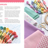 Floss, fabric, an embroidery hoop, scissors, and a needle from "Stitching Super-Cute Food Kawaii Style" by Schiffer Publishing, Ltd. are arranged on a pastel patterned surface—ideal for beginner or mix-and-match embroidery projects.