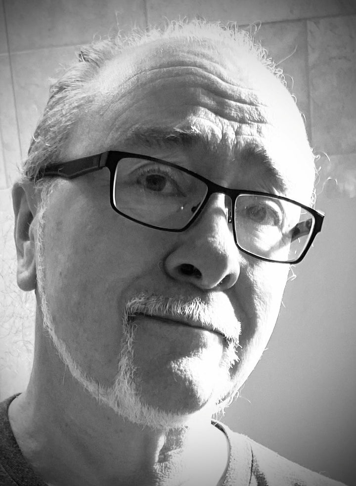 Black and white close-up photo of an older man with glasses, mustache, and goatee, gazing upward with a neutral expression. Light from the left highlights his face—he seems to ponder the mysteries of The Camelot Oracle by Schiffer Publishing, Ltd.