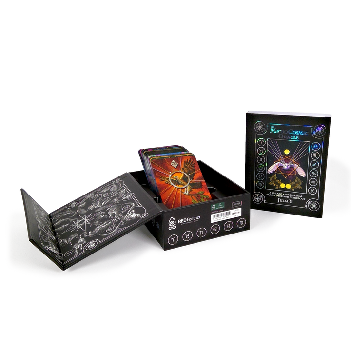 The MicroCosmic Oracle by Schiffer Publishing, Ltd. features a black illustrated box with vibrant divination cards inside—one displays a bird with outstretched wings. A cosmic-themed guidebook stands beside this astrology oracle deck.