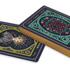The Weird Weavings Runic Oracle by Schiffer Publishing, Ltd. features a decorative playing card deck with ornate blue and green backs; one card shows a spider on a web with flowers, stars, and subtle Elder Futhark runes.