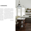 Inspired by Midwest Home from Schiffer Publishing, Ltd., this kitchen features dark cabinets, white countertops, a farmhouse sink, open wood shelves, a patterned rug on dark wood floors, large windows for natural light, and a pendant above the island.