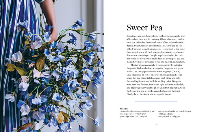 A woman in a blue-and-white striped dress holds a large bouquet of blue and white paper flowers beside a page from "Paper Flower Magic" by Schiffer Publishing, Ltd., displaying instructions for making crepe-paper blooms.