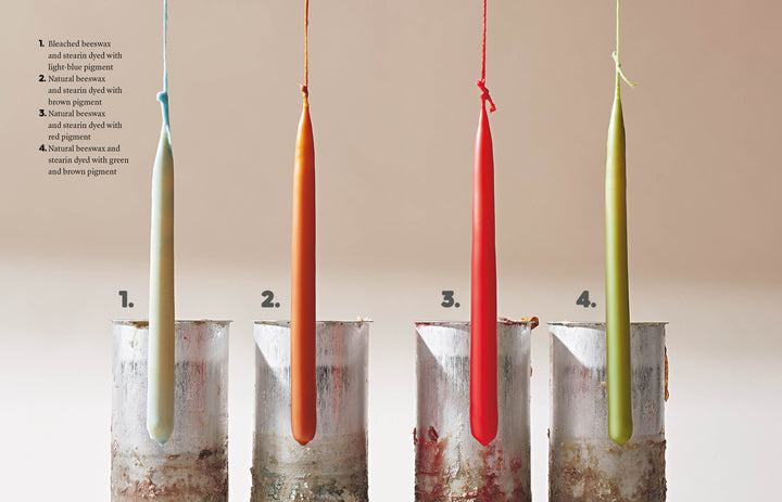 Four tall, slender candles—light beige, orange, red, and pale green—hang above metal molds with labels. Candle Whimsy by Schiffer Publishing, Ltd. is perfect for beginners or anyone exploring creative candle shapes.