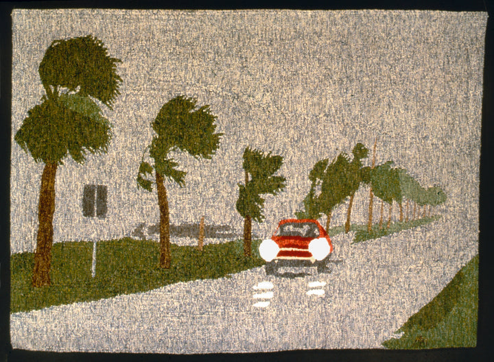 “Tapestry Talking” by Schiffer Publishing, Ltd. is a textured artwork inspired by tapestry weaving, depicting a red car with headlights on driving past windblown palms on a cloudy day.