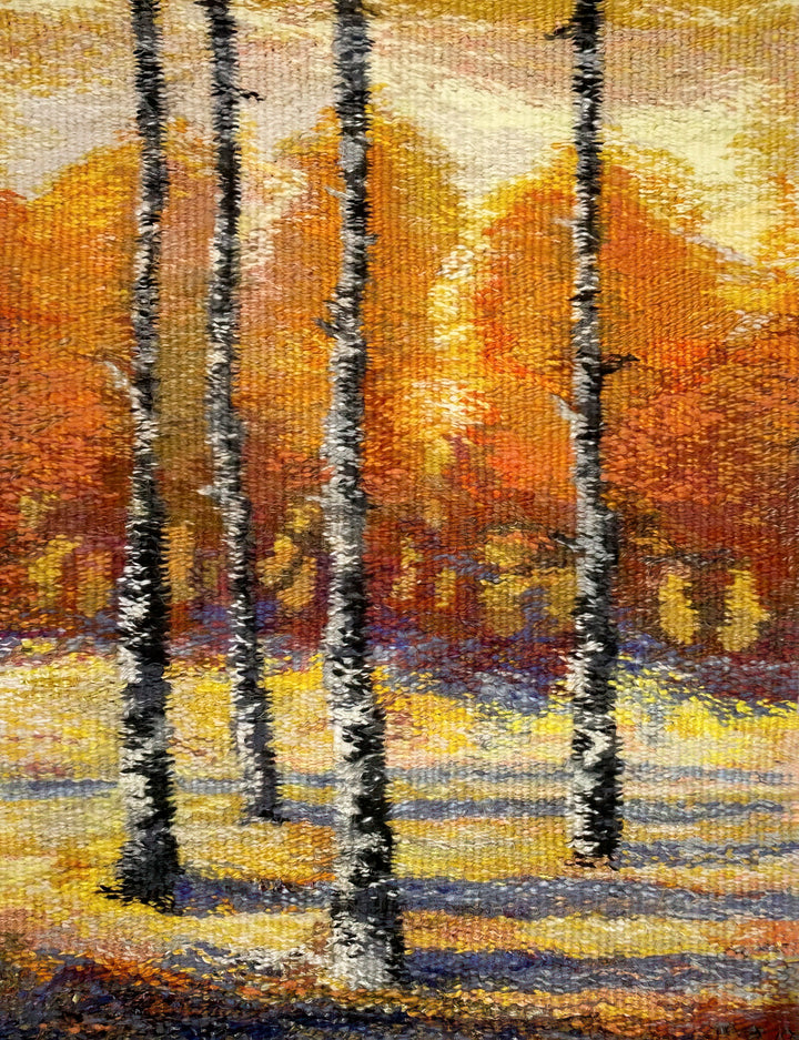 “Tapestry Talking” by Schiffer Publishing, Ltd. is a textured artwork inspired by tapestry weaving, showing slender birch trees with white bark and autumn’s vivid orange and yellow foliage cast with blue-purple shadows.