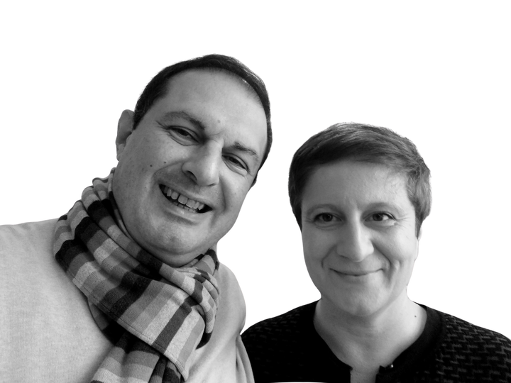 Two adults smile at the camera against a white background, their looks inspired by "10 Innovations That Will Shape Tomorrow's Architecture" from Schiffer Publishing, Ltd.—one in a checkered scarf and light sweater, the other in a dark top with short hair.