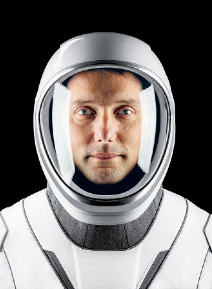 A person in a white and gray space helmet and suit, reminiscent of International Space Station photos, gazes at the camera—evoking the wonder found in Schiffer Publishing, Ltd.’s The Earth from Space Coloring Book.