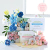The Bendable Blooms Chenille Stem Flower-Making Kit Botanical Blues by Schiffer Publishing, Ltd. is displayed with blue, pink, and white handmade chenille flowers. A pink circle reads: Collect Both Kits! Create your own DIY flower bouquet today!.