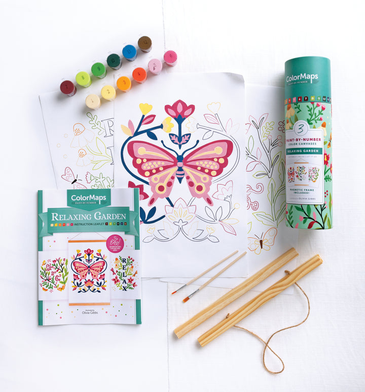 ColorMaps Paint-by-Number Relaxing Garden by Schiffer Publishing, Ltd. features a butterfly and floral design, paints, brushes, instructions, and rolled tube container. Some floral areas are partially painted and all items are on a white surface.