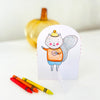 A hand-drawn card featuring a smiling squirrel in a hat and striped shirt stands upright beside three crayons, capturing the cozy charm of autumn-themed art. A yellow decorative pumpkin is softly blurred in the background—making this scene perfect inspiration for your next fall-themed coloring book or paper craft coloring book project with *Pumpkin Patch Pals* by Schiffer Publishing, Ltd.