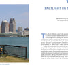 A striking view of Detroit’s skyline—modern and historic skyscrapers under a blue sky, seen from across the river with a grassy foreground—featured in "Detroit" by Schiffer Publishing, Ltd., ideal for Motor City souvenirs or photo books.