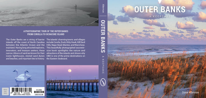 The book cover for Outer Banks by Schiffer Publishing, Ltd. features a pastel sunrise, wading birds, pier over calm sea, orange dune grasses, and iconic lighthouses of North Carolina’s Outer Banks. Back blurb describes the region. Author: Steve Alterman.