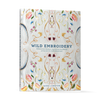 The cover of Wild Embroidery from Schiffer Publishing, Ltd. displays vibrant, detailed nature-inspired embroidery designs with the title and subtitle in blue and gold on a light fabric background.