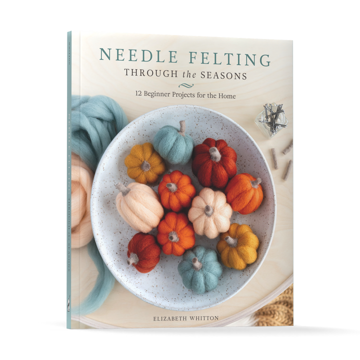 Needle Felting Through the Seasons by Schiffer Publishing, Ltd. features a cover with a white bowl of colorful felted pumpkins, wool fibers, and felting needles—ideal inspiration for your next needle felting project.