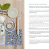 A flat lay of Schiffer Publishing, Ltd.'s "Needle Felting Through the Seasons" book and essential tools—felted wool balls, felting needles, safety eyes, yarn and circular needles, wool blocks, stitch markers, and templates—on a wood surface.