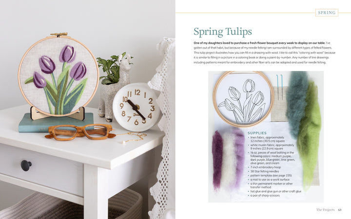 The book "Needle Felting Through the Seasons" by Schiffer Publishing, Ltd. is displayed on a white table with a gold clock, vase, colored pencils, and painted swatches showcasing step-by-step needle felting instructions and supplies.