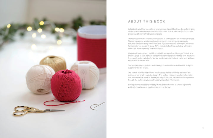 A photo showcases Cozy Christmas Crochet by Schiffer Publishing, Ltd.: cream, gold, and pink thread balls, red ribbon spool, embroidery scissors, and a needle on white. Blurred lit green branches add a hygge holiday crafts vibe; text appears to the right.