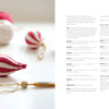 A close-up of handmade knit ornaments from "Cozy Christmas Crochet" by Schiffer Publishing, Ltd., featuring a red-and-white bauble, gold crocheted decor, yarn balls, and crochet hook—perfect for creating hygge-inspired holiday crafts.