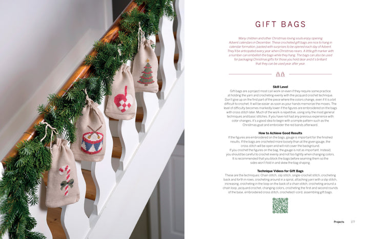 Six small fabric gift bags with cross-stitched holiday designs hang from a staircase railing decorated with evergreen garland and crocheted Christmas items from Cozy Christmas Crochet by Schiffer Publishing, Ltd. Text on the right shares tips for making gift bags.