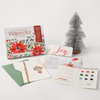 The Watercolor the Easy Way Paint-Your-Own Watercolor Cards Christmas kit by Schiffer Publishing, Ltd. includes a greeting card, paint samples, brush, color guide, instructions, and mini snow tree—ideal for making festive watercolor cards.