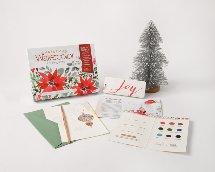 The Watercolor the Easy Way Paint-Your-Own Watercolor Cards Christmas kit by Schiffer Publishing, Ltd. includes a greeting card, paint samples, brush, color guide, instructions, and mini snow tree—ideal for making festive watercolor cards.
