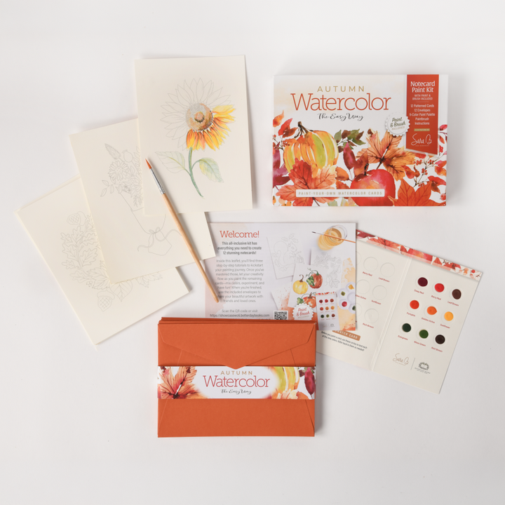 The Schiffer Publishing, Ltd. Watercolor the Easy Way Paint-Your-Own Watercolor Cards Autumn kit includes illustrated instructions, paint samples, a brush, floral watercolor sheets, a welcome card, and an orange envelope—ideal for watercolor enthusiasts.