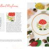 The Sunny Stitches Embroidery Kit Woodland Mushroom by Schiffer Publishing, Ltd. features a stitched red and white mushroom surrounded by grass, small flowers, and autumn leaves—perfect for creating a charming woodland embroidery scene.