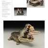 A page from "Humor in Craft" by Schiffer Publishing, Ltd. features three ceramic sculptures: sailors playing cards, three women together, and a large crocodile with a child inside—highlighting humor in contemporary craft.