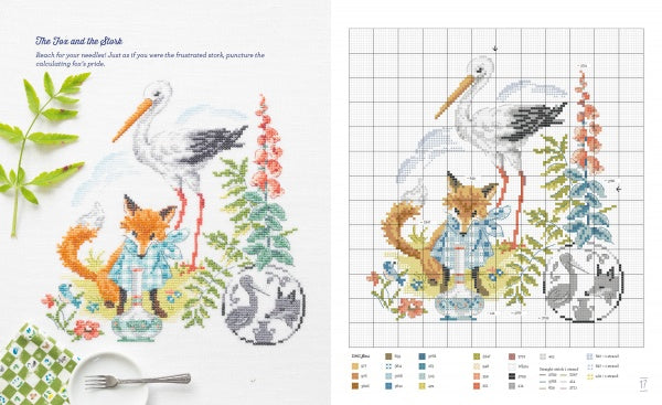 Fables & Fairy Tales to Cross Stitch by Schiffer Publishing, Ltd. offers a fairy tale pattern inspired by Véronique Enginger, with a fox in blue clothes, a stork, and a sleeping gray cat amidst flowers, greenery, and whimsical details.