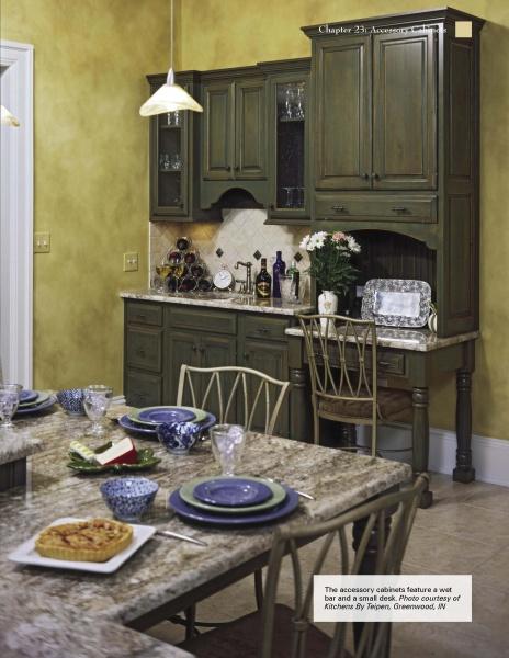 The Kitchen Guide by Schiffer Publishing, Ltd. showcases a kitchen with olive green cabinets, a built-in wet bar, marble countertops, and yellow walls. The dining table is set with blue dishes and features a pie and salad for an inviting touch.