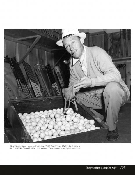 A man in a hat and sweater, pipe in hand, kneels by an open crate of golf balls, smiling with Golden Age Hollywood charm. Golf clubs are in the background. Product: Fade to Black by Schiffer Publishing, Ltd.