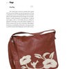 The Leather bag by Schiffer Publishing, Ltd. features a brown leather flap, long shoulder strap, and white floral appliqué. It's showcased next to a description and instructions for crafting—a great find for leather enthusiasts.