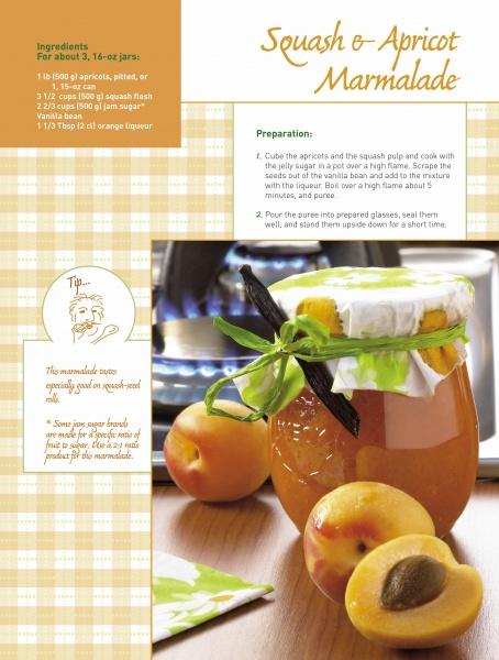 A jar of Schiffer Publishing, Ltd. Squash & Zucchini marmalade with a green ribbon sits on a table next to fresh apricots, a spoon, a cookbook, and an ingredients list in the background.