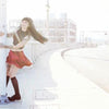 A woman with long dark hair and tattoos, wearing a red skirt and black top, smiles by a street pole in LA—an image capturing the spirit of AOI Ink Nymphs Los Angeles by Schiffer Publishing, Ltd., perfect for tattooed model features.