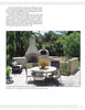 Relax or dine in a cozy patio with a stone fireplace and wood-fired oven, surrounded by greenery—perfect for testing gourmet recipes from The Ultimate Wood-Fired Oven Book by Schiffer Publishing, Ltd. Metal chairs and table complete the inviting scene.